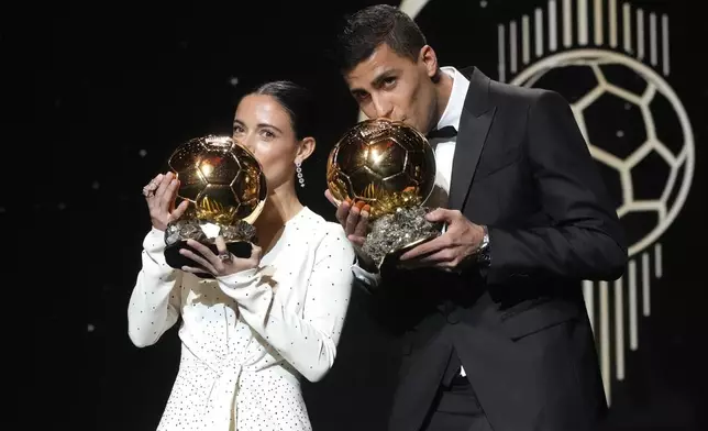 Barcelona's Spanish player Aitana Bonmati, left, and Manchester City's Spanish player Rodri kiss their 2024 Ballon d'Or trophies during the 68th Ballon d'Or (Golden Ball) award ceremony at Theatre du Chatelet in Paris, Monday, Oct. 28, 2024. (AP Photo/Michel Euler)