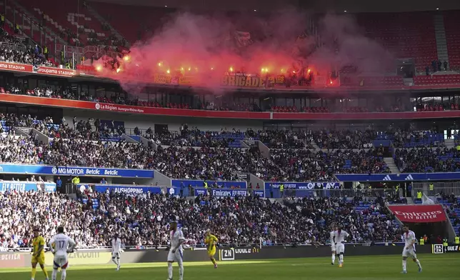 Nantes' fans burn flares during the French League One soccer match between Lyon and FC Nantes at the Groupama stadium in Decines, outside Lyon, France, Sunday, Oct. 6, 2024. (AP Photo/Laurent Cipriani)