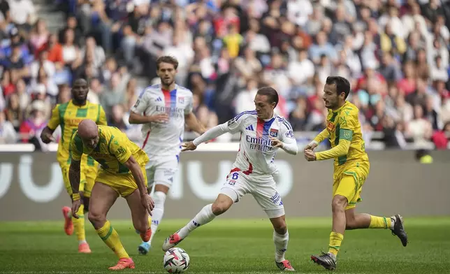 Lyon's Maxence Caqueret, center, dribbles the ball during the French League One soccer match between Lyon and FC Nantes at the Groupama stadium in Decines, outside Lyon, France, Sunday, Oct. 6, 2024. (AP Photo/Laurent Cipriani)