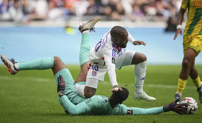 Lyon's Alexandre Lacazette, top, and Nantes' goalkeeper Alban Lafont fight for the ball during the French League One soccer match between Lyon and FC Nantes at the Groupama stadium in Decines, outside Lyon, France, Sunday, Oct. 6, 2024. (AP Photo/Laurent Cipriani)