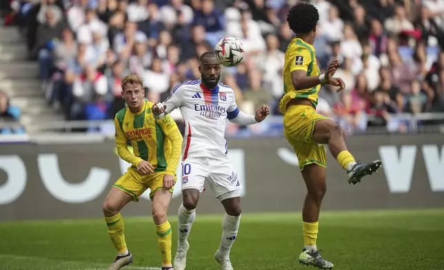 Lyon's Alexandre Lacazette, center, tries control the ball during the French League One soccer match between Lyon and FC Nantes at the Groupama stadium in Decines, outside Lyon, France, Sunday, Oct. 6, 2024. (AP Photo/Laurent Cipriani)