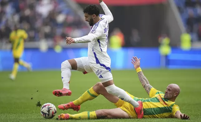 Nantes' Nicolas Pallois, bottom, challenges Lyon's Said Benrahma during the French League One soccer match between Lyon and FC Nantes at the Groupama stadium in Decines, outside Lyon, France, Sunday, Oct. 6, 2024. (AP Photo/Laurent Cipriani)