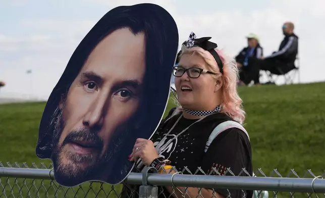 A fan holds a photo of Keanu Reeves as he drives during the GR Cup Series auto race at Indianapolis Motor Speedway, Saturday, Oct. 5, 2024, in Indianapolis. (AP Photo/Darron Cummings)