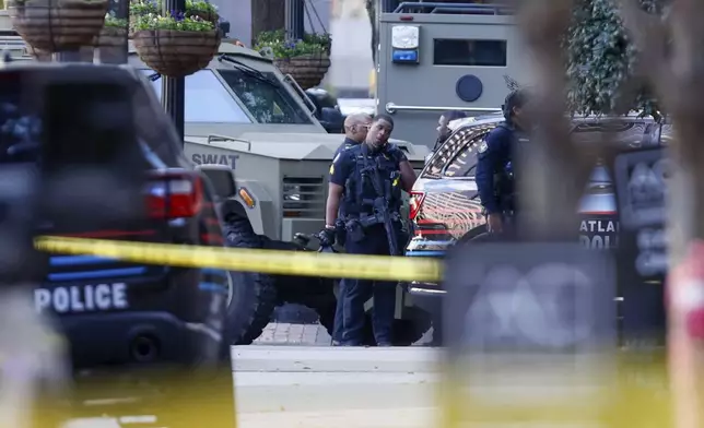 Members of the Atlanta Police Department and SWAT team stand on 14th Street outside the Four Seasons Hotel in the Midtown neighborhood of Atlanta, where a suspect fired shots inside the hotel Tuesday, Oct. 29, 2024. (Miguel Martinez/Atlanta Journal-Constitution via AP)