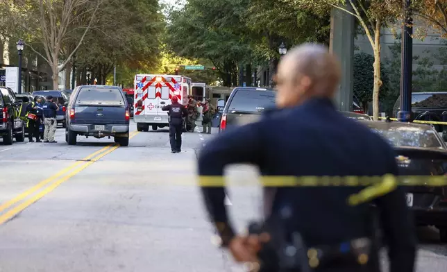 Atlanta Police officers and representatives from other agencies cleared the scene on 14th Street outside the Four Seasons Hotel in the Midtown neighborhood of Atlanta, Tuesday, Oct. 29, 2024, after a suspect was taken into custody following gunshots reported. (Miguel Martinez/Atlanta Journal-Constitution via AP)