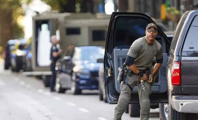 A SWAT team member adjusts his weapon on 14th Street outside the Four Seasons Hotel in the Midtown neighborhood of Atlanta, where a suspect fired shots inside the hotel Tuesday, Oct. 29, 2024. (Miguel Martinez/Atlanta Journal-Constitution via AP)