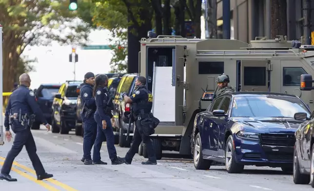 Members of the Atlanta Police Department and SWAT team stood on 14th Street outside the Four Seasons Hotel in Midtown Atlanta, where a suspect fired shots inside the hotel on Tuesday, Oct. 29, 2024. (Miguel Martinez/Atlanta Journal-Constitution via AP)