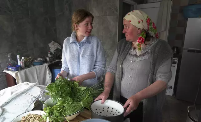 Svetlana Svetlishcheva, left, and her daughter Nina Strukova, right, talk as they cook dinner in their house in the remote mountain village of Orlovka, Georgia, Sunday, May 5, 2024. (AP Photo/Kostya Manenkov)