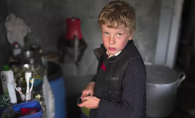 Ilya Strukov, 10, looks on in the kitchen as his family cooks dinner in their house in the remote mountain village of Orlovka, Georgia, Sunday, May 5, 2024. (AP Photo/Kostya Manenkov)