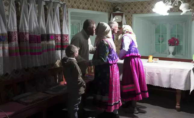 Yuri Strukov, second left, his son Ilya, left, and his daughters Daria and Nina in traditional Doukhobor dresses embrace each other after Easter prayer at the former Orphanage house where Doukhobors has worshiped for years, in the remote mountain village of Gorelovka, Georgia, Saturday, May 4, 2024. (AP Photo/Kostya Manenkov)