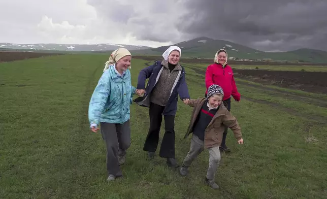 Nina Strukova, Daria Strukova, Ilya Strukov and their mother Svetlana Svetlishcheva walk to a cemetery outside the remote mountain village of Orlovka, Georgia, Saturday, May 5, 2024. (AP Photo/Kostya Manenkov)