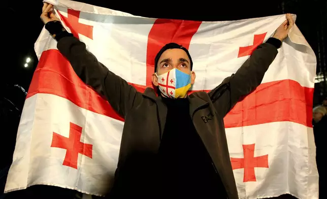 A man holds a Georgian flag during an opposition protest against the results of the parliamentary election in Tbilisi, Georgia, Monday, Oct. 28, 2024. (AP Photo/Shakh Aivazov)