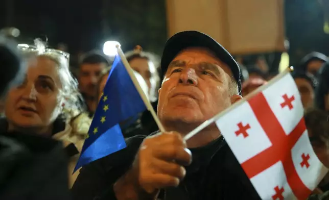 A demonstrator holds an EU and a Georgian national flags attending an opposition protest against the results of the parliamentary election in Tbilisi, Georgia, on Monday, Oct. 28, 2024. (AP Photo/Zurab Tsertsvadze)