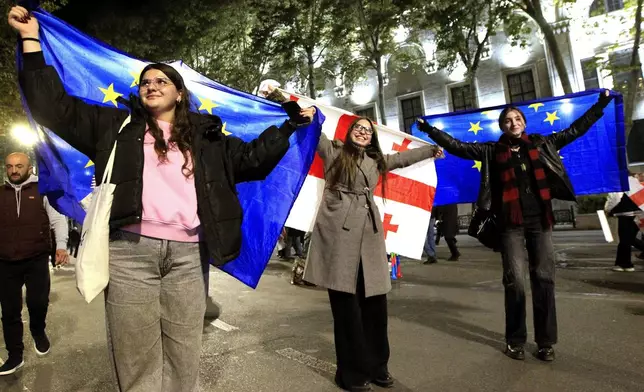 People hold EU and Georgian flags during an opposition protest against the results of the parliamentary election in Tbilisi, Georgia, Monday, Oct. 28, 2024. (AP Photo/Shakh Aivazov)