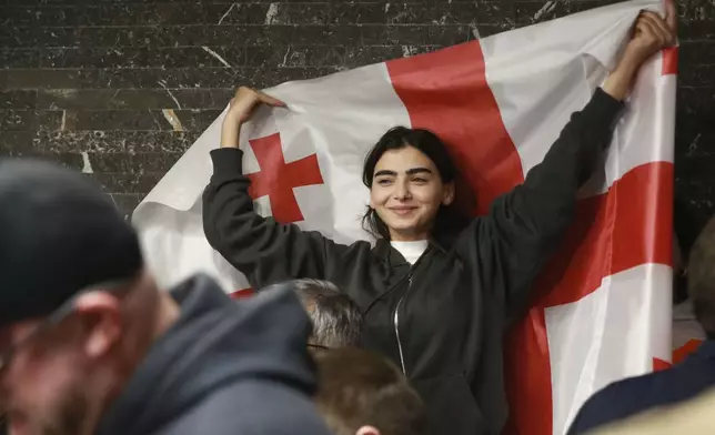 A supporter of the Coalition for Change holds a Georgian flag at coalition's headquarters after polls closing at the parliamentary election in Tbilisi, Georgia, Saturday, Oct. 26, 2024. (AP Photo/Zurab Tsertsvadze)
