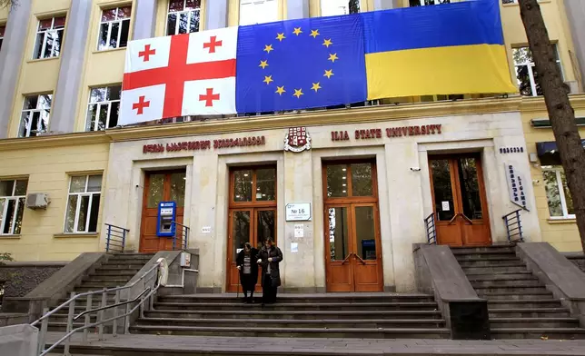 From left: Georgian national, EU and Ukrainian national flags hangs at a polling station during the parliamentary election in Tbilisi, Georgia, Saturday, Oct. 26, 2024. (AP Photo/Shakh Aivazov)