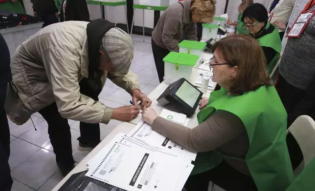 People get their ballots at a polling station during the parliamentary election in Tbilisi, Georgia, Saturday, Oct. 26, 2024. (AP Photo/Zurab Tsertsvadze)