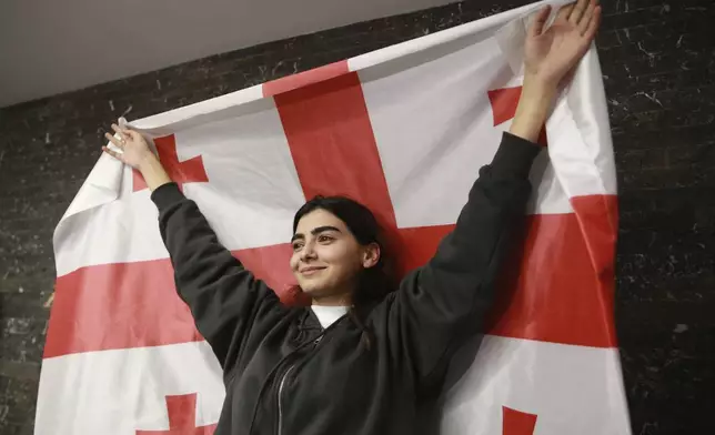 A supporter of the Coalition for Change holds a Georgian flag at coalition's headquarters after polls closing at the parliamentary election in Tbilisi, Georgia, Saturday, Oct. 26, 2024. (AP Photo/Zurab Tsertsvadze)