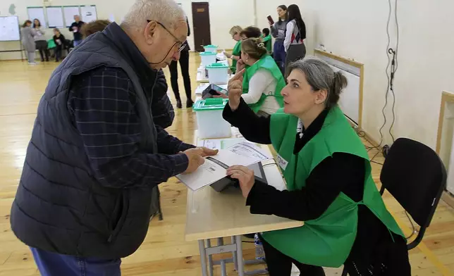A man gets his ballot at a polling station during the parliamentary election in Tbilisi, Georgia, Saturday, Oct. 26, 2024. (AP Photo/Shakh Aivazov)