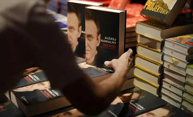 A woman arranges copies of the late Russian opposition leader Alexei Navalny's memoir entitled 'Patriot' are put display on the first day of sale in a bookshop in Berlin, Germany, Tuesday, Oct. 22, 2024. (AP Photo/Markus Schreiber)