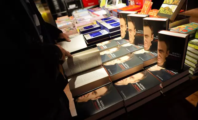 Customers look at copies of the late Russian opposition leader Alexei Navalny's memoir entitled 'Patriot' are put display on the first day of sale in a bookshop in Berlin, Germany, Tuesday, Oct. 22, 2024. (AP Photo/Markus Schreiber)