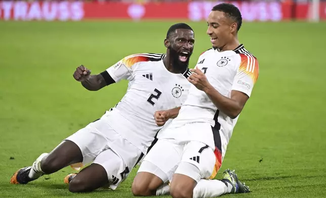 Germany's scorer Jamie Leweling, right, celebrates with teammate Antonio Ruediger after scoring the opening goal during the UEFA Nations League group 3 soccer match between Germany and The Netherlands in Munich, Germany, Monday, Oct. 14, 2024. (Sven Hoppe/dpa via AP)