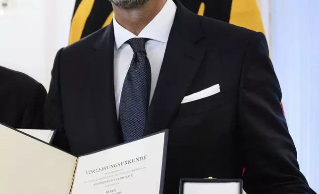 Jurgen Klopp stand in Bellevue Palace after receiving the Order of Merit of the Federal Republic of Germany and show his certificates as Federal President Steinmeier honors 28 citizens on the Day of German Unity, in Berlin, Tuesday, Oct. 1, 2024. (Bernd von Jutrczenka/dpa via AP)