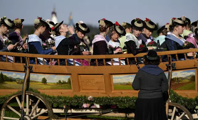 Women in traditional costumes of the region drink Schnaps after the traditional Leonhardi pilgrimage in Warngau near Munich, Germany, Sunday, Oct. 27, 2024. The annual pilgrimage honors St. Leonhard, patron saint of the highland farmers for horses and livestock. (AP Photo/Matthias Schrader)