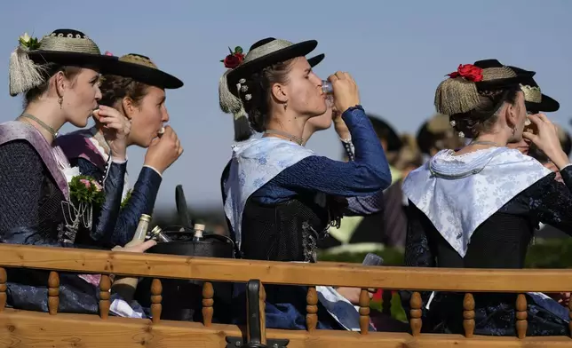 Women in traditional costumes of the region drink Schnaps after the traditional Leonhardi pilgrimage in Warngau near Munich, Germany, Sunday, Oct. 27, 2024. The annual pilgrimage honors St. Leonhard, patron saint of the highland farmers for horses and livestock. (AP Photo/Matthias Schrader)