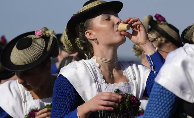 Women in traditional costumes of the region drink Schnaps after the traditional Leonhardi pilgrimage in Warngau near Munich, Germany, Sunday, Oct. 27, 2024. The annual pilgrimage honors St. Leonhard, patron saint of the highland farmers for horses and livestock. (AP Photo/Matthias Schrader)