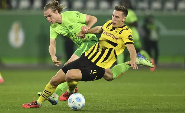 Dortmund's Nico Schlotterbeck, right, battles for the ball with Wolfsburg's Patrick Wimmer during a second-round German Cup soccer match, Tuesday, Oct. 29, 2024, in Wolfsburg, Germany. (Swen Pförtner/dpa via AP)