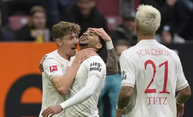 Augsburg's Alexis Claude-Maurice, centre, celebrates with Augsburg's Kristijan Jakic, left, after scoring his side's opening goal during the Bundesliga soccer match between FC Augsburg and Borussia Dortmund at WWK-Arena, Augsburg, Germany, Saturday, Oct. 26, 2024. (AP Photo/Matthias Schrader)