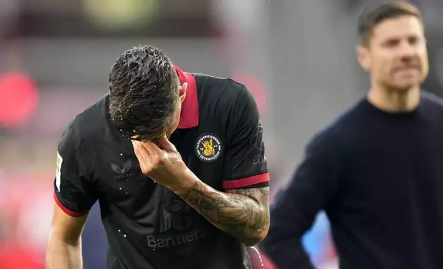 Leverkusen's Piero Hincapie reacts beside Leverkusen's head coach Xabi Alonso after not winning the German Bundesliga soccer match between Bayer Leverkusen and Holstein Kiel at the BayArena in Leverkusen, Germany, Saturday, Oct. 5, 2024. (AP Photo/Martin Meissner)