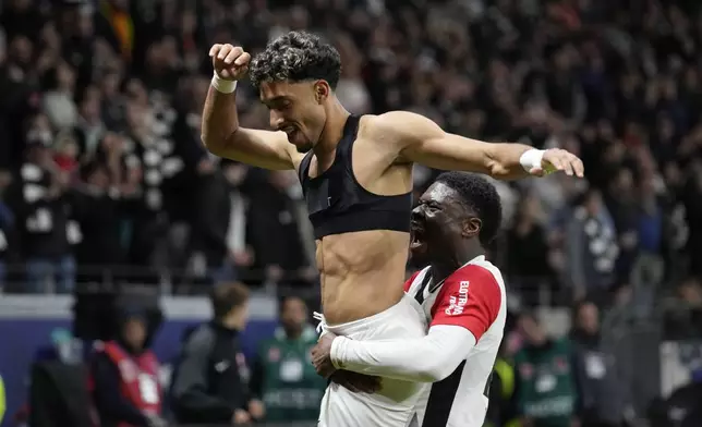 Frankfurt's Omar Marmoush, top, celebrates after scoring his side's third goal during the German Bundesliga soccer match between Eintracht Frankfurt and Bayern Munich in Frankfurt, Germany, Sunday, Oct. 6, 2024. (AP Photo/Michael Probst)