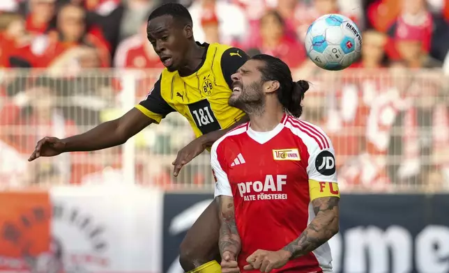 Dortmund's Sebastien Haller, left, and Union's Christopher Trimmel jump for the ball during the Bundesliga soccer match between Union Berlin and Borussia Dortmund in Berlin, Germany, on Saturday, Oct. 5, 2024. (AP Photo/Ebrahim Noroozi)