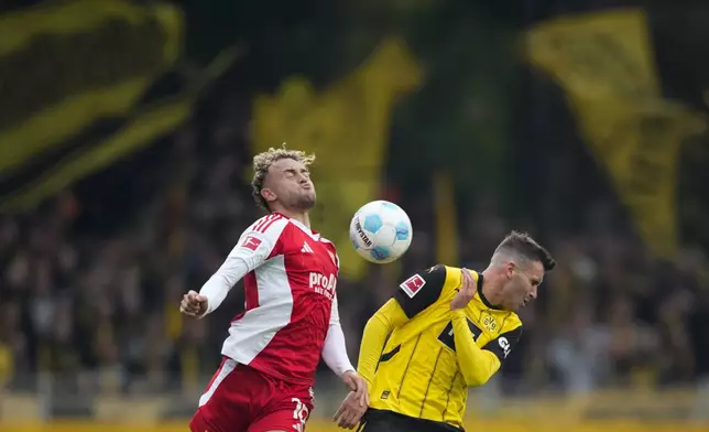 Union's Benedict Hollerbach, left, and Dortmund's Pascal Gross jump for the ball during the Bundesliga soccer match between Union Berlin and Borussia Dortmund in Berlin, Germany, on Saturday, Oct. 5, 2024.(AP Photo/Ebrahim Noroozi)