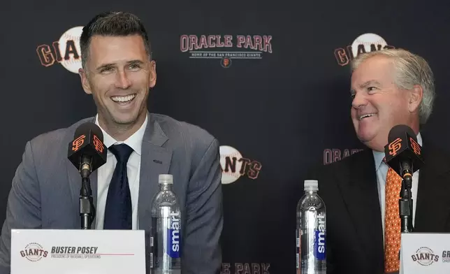 San Francisco Giants president of baseball operations Buster Posey, left, smiles next to chairman Greg Johnson during a news conference in San Francisco, Tuesday, Oct. 1, 2024. (AP Photo/Jeff Chiu)