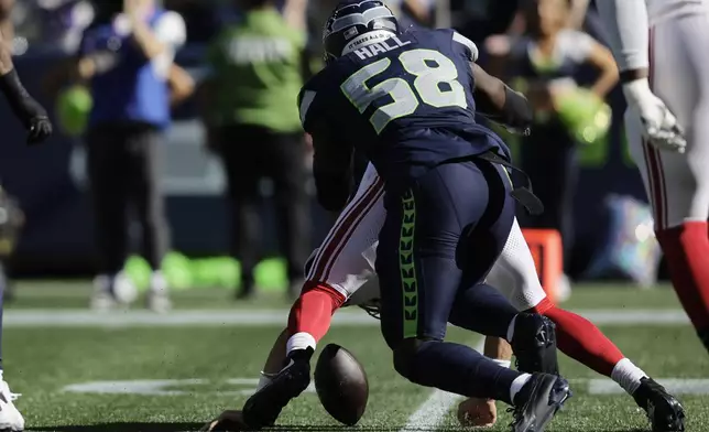 New York Giants quarterback Daniel Jones (8) fumbles while hit by Seattle Seahawks linebacker Derick Hall (58) during the first half of an NFL football game, Sunday, Oct. 6, 2024, in Seattle. (AP Photo/John Froschauer)