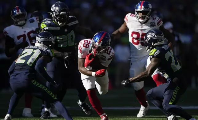 New York Giants running back Tyrone Tracy Jr. (29) runs with the football as Seattle Seahawks cornerbacks Devon Witherspoon (21), left, and Tre Brown (22), right, look to tackle during the second half of an NFL football game, Sunday, Oct. 6, 2024, in Seattle. (AP Photo/Lindsey Wasson)