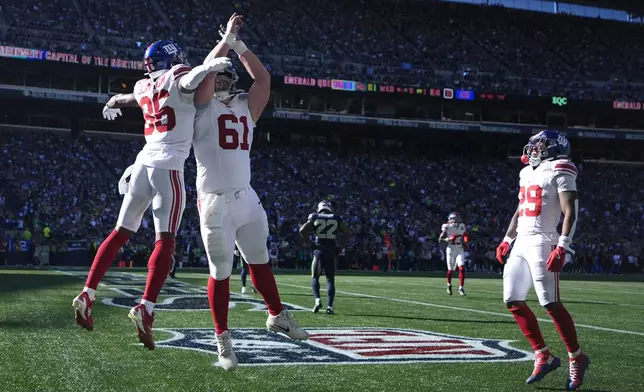 New York Giants wide receiver Darius Slayton (86), left, celebrates with teammates after scoring a 30-yard touchdown during the second half of an NFL football game against the Seattle Seahawks, Sunday, Oct. 6, 2024, in Seattle. (AP Photo/Lindsey Wasson)