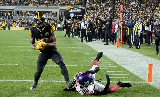 Pittsburgh Steelers wide receiver Calvin Austin III (19) catches a touchdown next to New York Giants cornerback Dru Phillips (22) during the second half of an NFL football game Monday, Oct. 28, 2024, in Pittsburgh. (AP Photo/Gene J. Puskar)