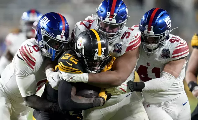 Pittsburgh Steelers running back Najee Harris (22) is tackled by New York Giants linebacker Brian Burns (0) defensive tackle Dexter Lawrence II (97) and linebacker Micah McFadden (41) during the second half of an NFL football game Monday, Oct. 28, 2024, in Pittsburgh. (AP Photo/Gene J. Puskar)