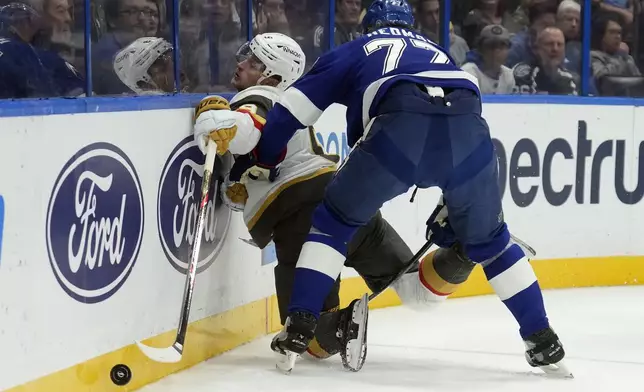 Tampa Bay Lightning defenseman Victor Hedman (77) checks Vegas Golden Knights center Jack Eichel (9) into the boards during the first period of an NHL hockey game Thursday, Oct. 17, 2024, in Tampa, Fla. (AP Photo/Chris O'Meara)