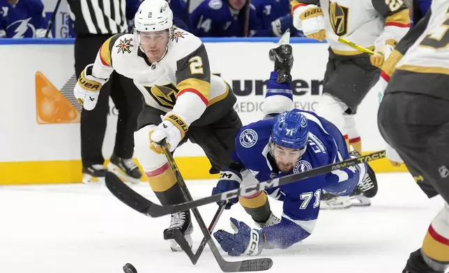 Tampa Bay Lightning center Anthony Cirelli (71) goes down while chasing the puck with Vegas Golden Knights defenseman Zach Whitecloud (2) during the second period of an NHL hockey game Thursday, Oct. 17, 2024, in Tampa, Fla. (AP Photo/Chris O'Meara)