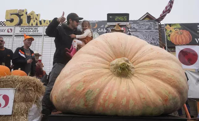 Brandon Dawson, of Sonoma County, foreground left, celebrates with his daughter Ayla, 3, after his pumpkin weighed in at 2,465 pounds at the Safeway World Championship Pumpkin Weigh-Off in Half Moon Bay, Calif., Monday, Oct. 14, 2024. (AP Photo/Jeff Chiu)