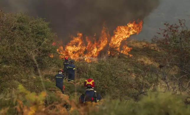 Firefighters try to extinguish the flames during a third day of a wildfire, in Sofiana village, about 142 kilometers (88 miles) west of Athens, Greece, on Tuesday, Oct. 1, 2024. (AP Photo/Petros Giannakouris)