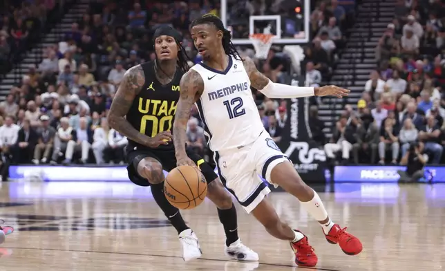 Memphis Grizzlies guard Ja Morant (12) dribbles past Utah Jazz guard Jordan Clarkson (00) during the first half of an NBA basketball game, Wednesday, Oct. 23, 2024, in Salt Lake City. (AP Photo/Rob Gray)