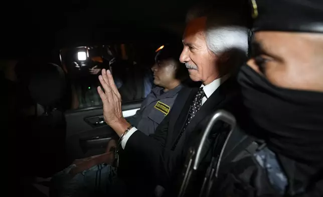 Guatemalan journalist Jose Ruben Zamora, founder of El Periodico newspaper, jailed for more than two years on money laundering charges, waves from inside a police car after a judge granted him house arrest, in Guatemala City, Friday, Oct. 18, 2024. (AP Photo/Moises Castillo)