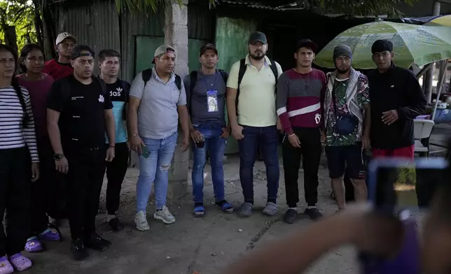 Venezuelan migrants stand in line to have their photo taken by a smuggler as proof that they paid the passage fee to cross from Tecun Uman, Guatemala to Tapachula, Mexico, Tuesday, Oct. 29, 2024. (AP Photo/Matias Delacroix)