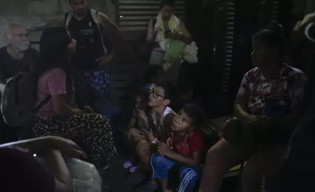 Venezuelan migrant Daniel Dura, second from right, waits next to his mother Rannely Duran inside a house before crossing the Suchiate River, which marks the border between Guatemala and Mexico, from Tecun Uman, Guatemala, Sunday, Oct. 27, 2024. (AP Photo/Matias Delacroix)